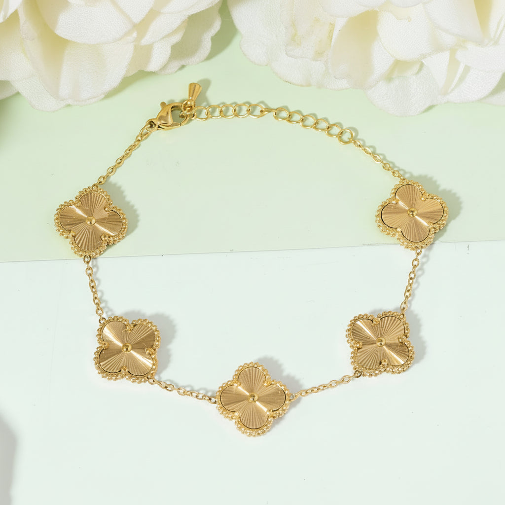 Gold bracelet with clover-shaped links on a light green and white background
