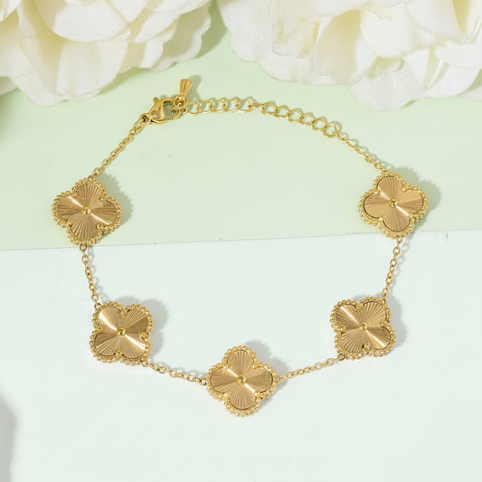 Gold bracelet with clover-shaped links on a light green and white background