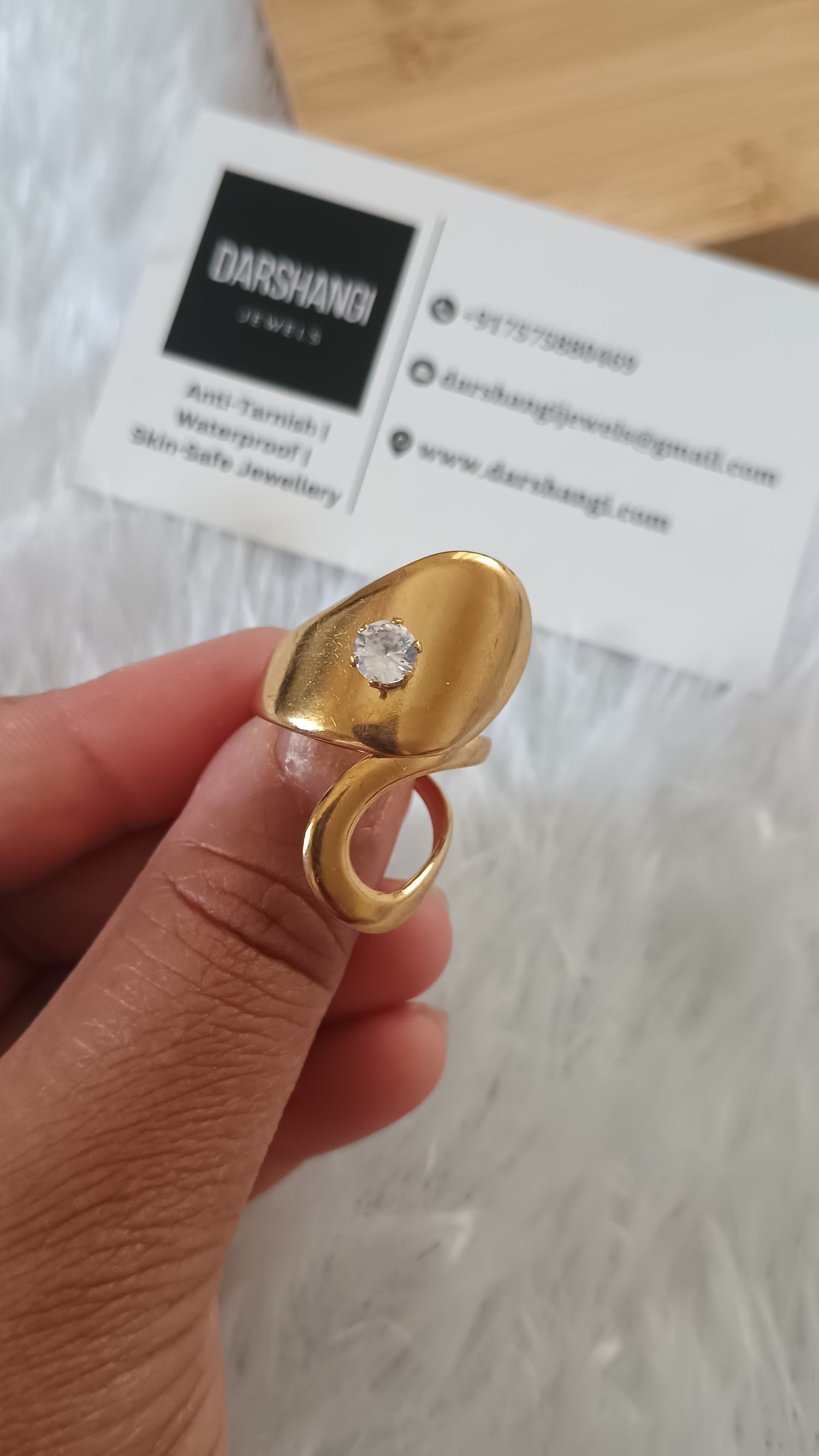 Gold ring with a diamond held by a hand on a blurred background