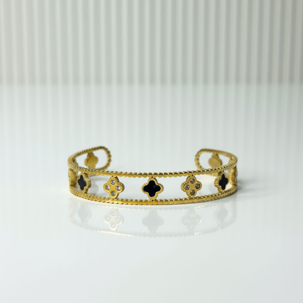 Gold bracelet with black clover designs on a white background