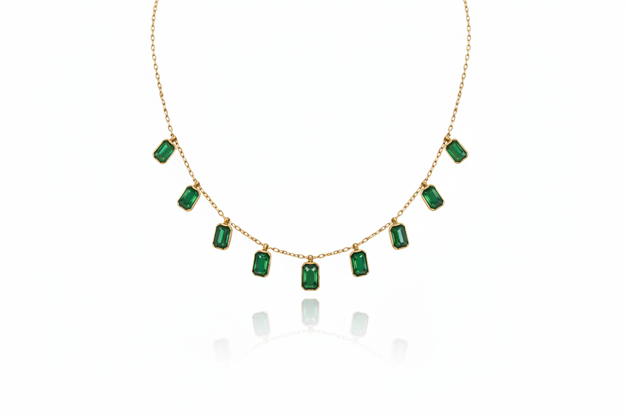 Gold necklace with emerald green gemstones on a white background