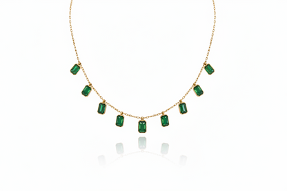 Gold necklace with emerald green gemstones on a white background
